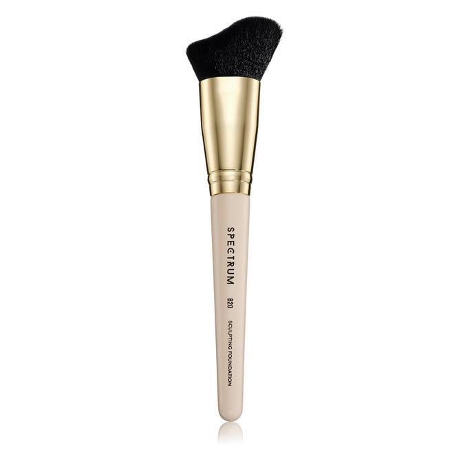 Makeup brush with black bristle tip and gold and beige handle on a white background